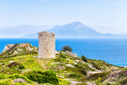 A view of a simple round tower near the sea, with an island in the background