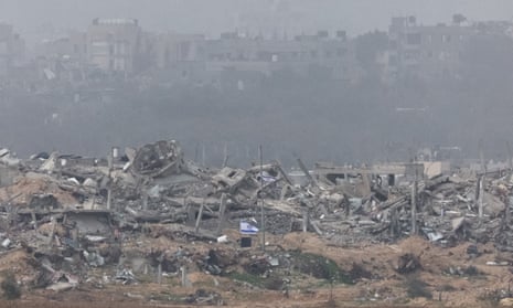 Israeli flags fly next to the rubble of destroyed buildings in Gaza, as seen from southern Israel.