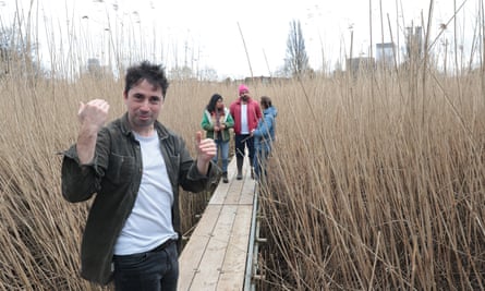 Man in dark green jacket amid reeds with three other people in background