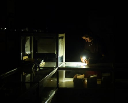 A man works inside a pharmacy during a blackout
