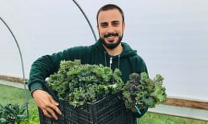 Hassan Ali stands with a box of fresh kale.