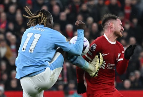 Manchester City's Belgian midfielder Jeremy Doku (L) kicks Liverpool's Argentinian midfielder Alexis Mac Allister in the chest.