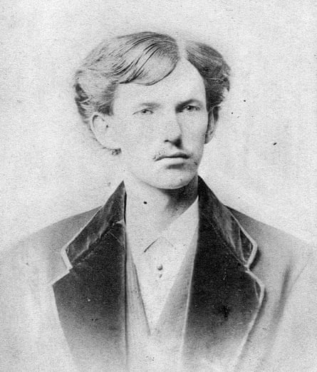 An old black-and-white photo of a young man in an overcoat