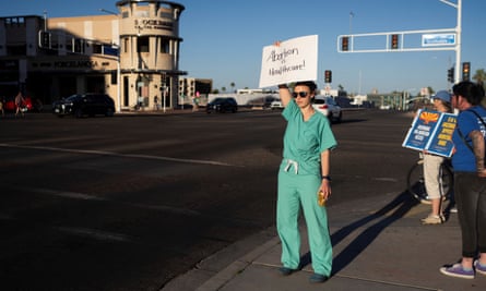 Woman in scrubs holds sign calling for abortion rights