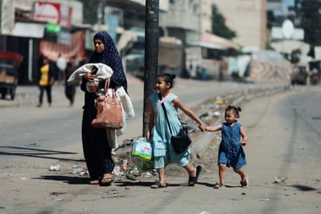 A Palestinian mother and her two young daughters walk with their belongings as they flee Rafah.
