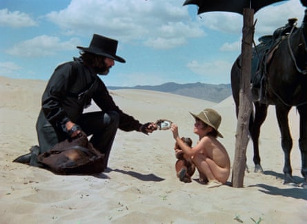 A cowboy, a small boy and a horse in the desert.