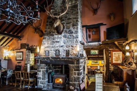 Interior of a cosy pub with large stone fireplace with a stag’s head attached