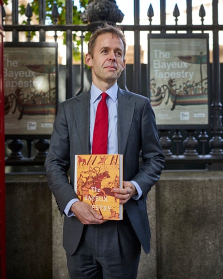 Harris stands in front of railings holding a copy of the exhibition book
