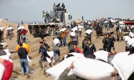 People carrying bags of flour next to a truck