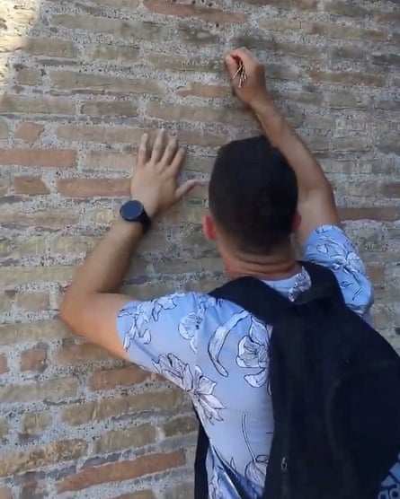 A tourist carves on the wall at the Colosseum
