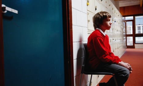 Schoolboy sitting on chair in corridor