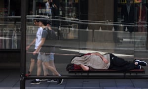 A man is seen sleeping in a bus shelter outside the Queen Victoria Building in Sydney, 23 January 2019.