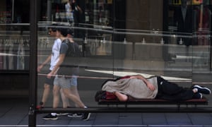 A man is seen sleeping in a bus shelter outside the Queen Victoria Building in Sydney, 23 January 2019.