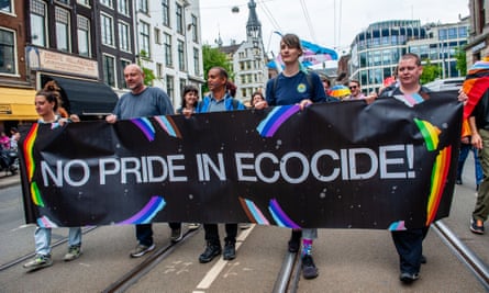 People are seen holding a big banner against ecocide during a Pride event in Amsterdam, July 2023.