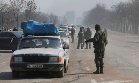 Service members of pro-Russian troops stand guard at a checkpoint in the besieged city of Mariupol