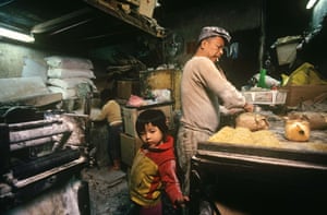 Greg Girard, Family-run noodle factory that is a workshop by day and a home in the evening.Hui Tung Choy at work in his tiny noodle-making factory, barely 200 square feet in area. Without windows, the only ventilation came from the narrow doorway where it opened on to Kwong Ming Street, one of the Cityâs larger alleys but itself lacking in an overabundance of fresh air. Unsurprisingly, like most factories in the City, working conditions during the summer months could be gruelling. His two daughters would often join Hui and his wife in the factory after school.