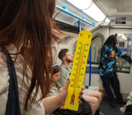 The writer holding a thermometer showing the temperature above 30C.