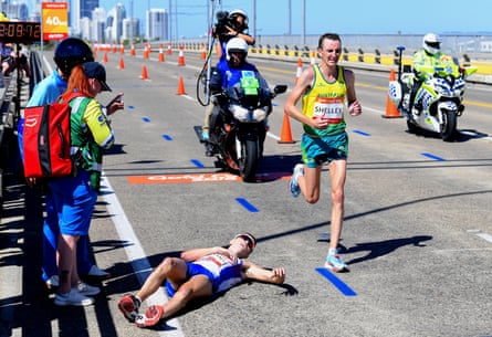 Scotland’s Callum Hawkins lies on the ground as Australia’s Michael Shelley runs past during the Men’s Marathon.