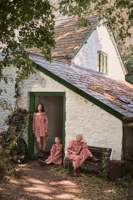 two women and a young girl wear gingham by a white cottages