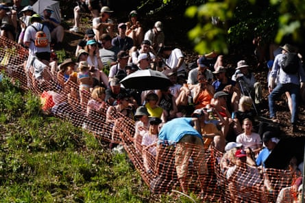 Crowds behind a plastic fence, with umbrellas, trying to stay in the shade