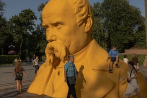 People walk around and climb on a large bust of the Ukrainian poet Taras Shevchenko