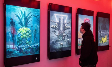 A man looks at digital paintings by US artist Beeple at an NFT exhibition.