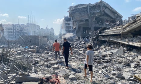 three people walk through rubble amid devastation of a street after an Israeli airstrike, in the El-Remal area of Gaza City, 10 October 2023