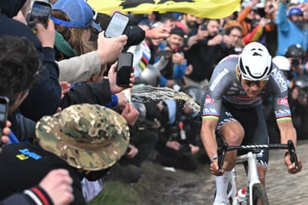 A spectator spills liquid as Mathieu van der Poel cycles past
