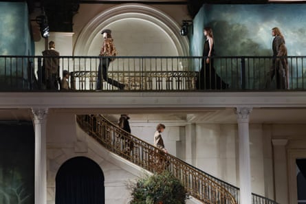 Models walk along balcony and down stairs on catwalk set.