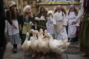 Girls lead a gaggle of geese, backdropped by a banner against the war in Ukraine, during a Saint Martin’s Day procession next to the Charles Bridge in Prague