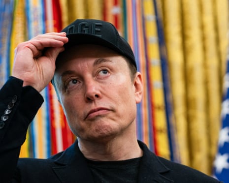 Elon Musk wearing a black cap that says ‘Doge’