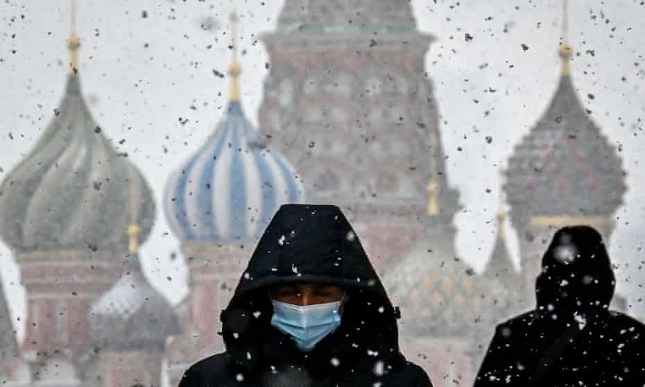 A man wearing a facemask in Red Square, Moscow, with the Saint Basil cathedral on the background 