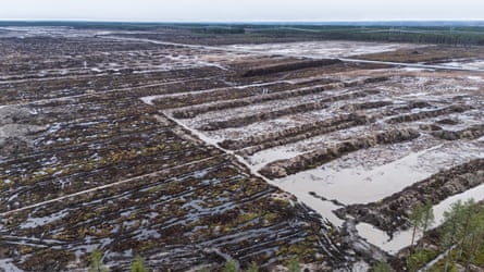 Aerial view of a vast clearcut landscape near Muhos, Finland, with stripped soil and water pools.