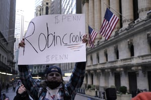 A demonstrator holds up a placard in front of the New York Stock Exchange, hours after Robinhood, an online stock trading company, restricted their users from trading the popular GameStop stocks.