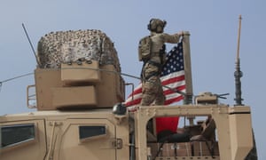 An American soldier mounts the US flag on a vehicle near the town of Tel Tamr in northern Syria.