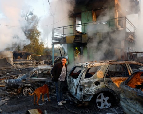 A resident with a dog looks on at the site of private car garages hit by a Russian missile strike in Kyiv, Ukraine.