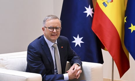 Anthony Albanese is sitting on a white armchair next to Australian, Spanish and EU flags
