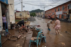 A woman wipes mud at the entrance of a restaurant in a flooded street at Taishitun.