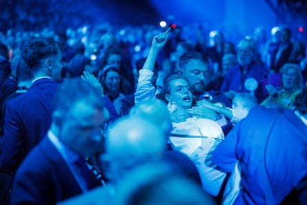 A woman raising her fist into the air as she's being carried out by a number of men