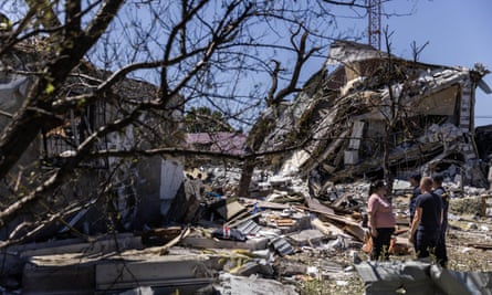 A woman speaks with emergency service workers after a Russian airstrike of the residential community, Pidhorodne, a town north of Dnipro, Ukraine