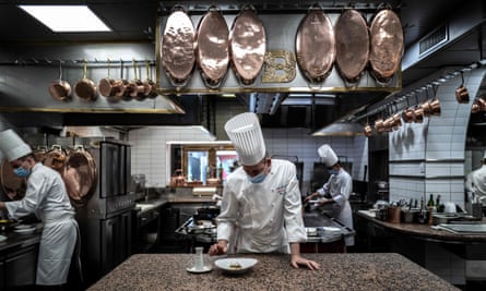 French chef Gilles Reinhardt (C) prepares frog legs in the Restaurant of Paul Bocuse
