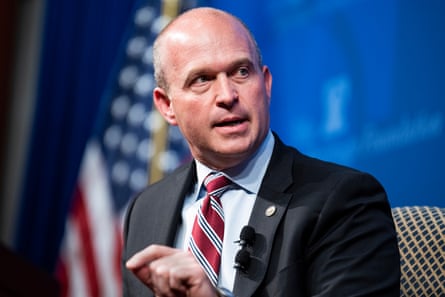 A man in a suit and tie speaks on stage.