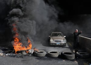 A Maronite priest pleads with anti-government protesters to let him pass with his vehicle as he stands next to burning tyres at a makeshift roadblock in Zouk Mosbeh