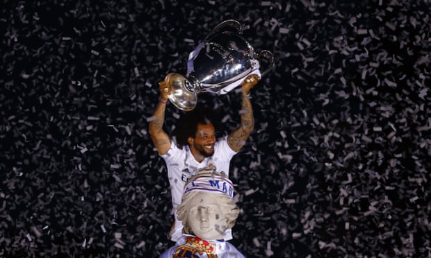 Marcelo poseert met de Champions League-trofee bovenop een fontein waar confetti omheen valt.