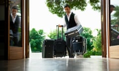 A porter carries suitcases into a hotel.