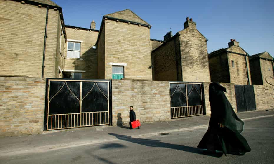 A mother and child walk by terraced houses in the Manningham area of Bradford.