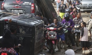People squeeze past cars piled up by flooding in Jakarta