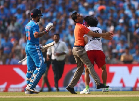 A pitch invader gets hauled away by the security team.