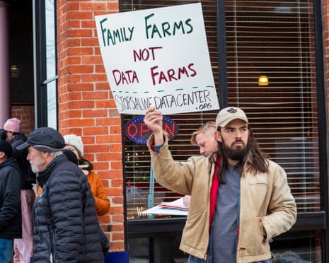 a person holds a sign that reads 'family farms not data farms'