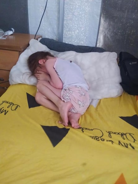 A very thin looking Jana curled up on a bed crying